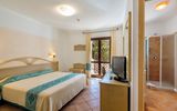 Helles und freundlich eingerichtetes Hotelzimmer mit Doppelbett, Schreibtisch, Fernseher und Zugang zum Balkon – Blick ins angrenzende Bad mit Dusche.