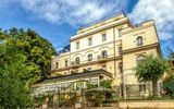 Stilvolles Hotel mit eleganter Fassade in ruhiger Lage, umgeben von viel Grün – idealer Ausgangspunkt für einen komfortablen und erlebnisreichen Urlaub in Italien.