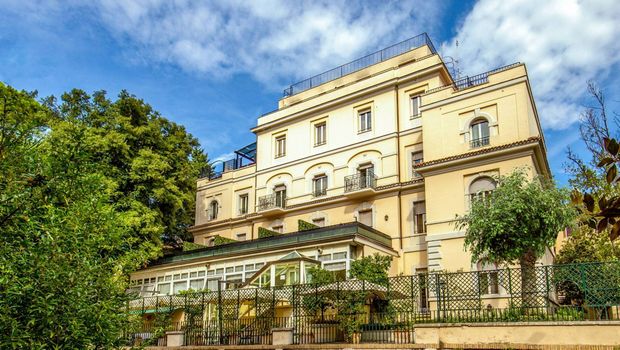 Stilvolles Hotel mit eleganter Fassade in ruhiger Lage, umgeben von viel Grün – idealer Ausgangspunkt für einen komfortablen und erlebnisreichen Urlaub in Italien.