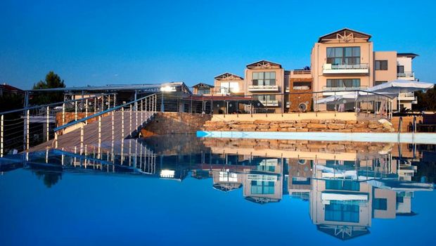 Modernes Hotel mit eleganter Fassade in ruhiger Lage – der große Infinity-Pool spiegelt das Gebäude eindrucksvoll und sorgt für eine stimmungsvolle Urlaubskulisse.