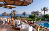 Genießen Sie ein stilvolles Abendessen auf der Terrasse mit Blick auf Palmen, Pool und das weite Meer – perfekt zum Sonnenuntergang.