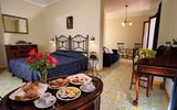 Gemütliches Doppelzimmer mit traditionellem Mobiliar, gemustertem Fliesenboden und separatem Sitzbereich – auf dem Tisch ein liebevoll angerichtetes Frühstückstablett mit Kaffee, Gebäck und frischen Blumen.