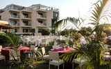 Stilvoll gedeckte Tische auf einer gepflegten Gartenanlage vor einem modernen Hotelgebäude – die perfekte Kulisse für ein romantisches Dinner unter freiem Himmel.