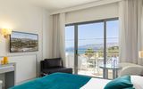 Modern eingerichtetes Zimmer mit Balkon und traumhaftem Blick über das tiefblaue Meer bis hin zur malerischen Küste.