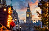 Beautiful sunset view of the Big Ben Clocktower in London, England, with the fairy lights from the Trafalgar Square Christmas market in front