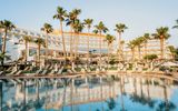 Großzügiger Poolbereich mit Liegen unter Palmen – ideal zum Entspannen und Genießen der Sonne direkt vor dem eleganten Hotelgebäude.