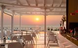 Stilvolle Hotelbar mit weißem Interieur und traumhaftem Blick auf das Meer – ideal, um den Sonnenuntergang bei einem Cocktail in entspannter Atmosphäre zu genießen.