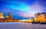 Nordlichter über dem gefrorenen Hafen in Katajanokka mit der orthodoxen Uspenski-Kathedrale in Helsinki