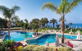 Luxuriöser Pool mit Meerblick, umgeben von Palmen, Blumen und Liegen – perfekte Wohlfühloase.