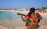 Musician with guitar and rasta hair at Santa Maria Beach, Sal
