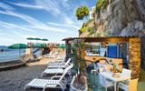 Sandstrand mit Liegen und Bar am Hotel La Madonnina auf Ischia, Italien