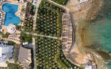 Großzügige Gartenanlage mit Schatten spendenden Palmen und zahlreichen Sonnenschirmen – direkt am feinsandigen Strand und kristallklaren Meer gelegen.
