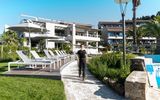 Moderne Hotelanlage mit stilvoller Architektur, großzügigem Poolbereich und komfortablen Sonnenliegen – umgeben von Palmen, Grünflächen und mediterranem Flair.