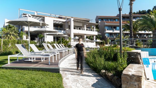 Moderne Hotelanlage mit stilvoller Architektur, großzügigem Poolbereich und komfortablen Sonnenliegen – umgeben von Palmen, Grünflächen und mediterranem Flair.