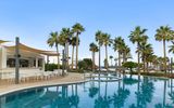 Stilvolle Poolbar mit bequemen Sitzmöglichkeiten – umgeben von Palmen und nur wenige Schritte vom Strand entfernt.