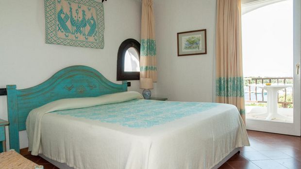 hell eingerichtetes Zimmer mit Balkon im Hotel Luci di la Muntagna auf Sardinien in Italien